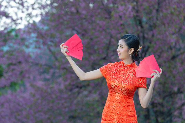 东方美丽的亚洲女人在中国的新年里展示一些东西和拿红包中国复制空间微笑
