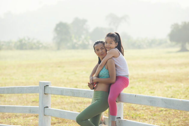慢跑可爱的小女儿和妈妈一起骑在背驮上 在乡下度过了一段时间在大自然里 夏天的草地上有一个幸福的家庭户外运动与健身 运动学习促进儿童发展活动休闲享受