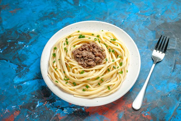 一餐前视图美味的意大利面食与地面肉和叉子上的蓝色面团食物菜颜色的一餐面团叉子意大利面