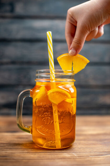 前面正面图新鲜橙汁罐内用吸管放在深色吧台上水果色鸡尾酒饮料蜂蜜玻璃杯食物