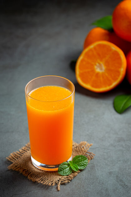 橙子新鲜的橙汁在黑暗的背景玻璃刷新木头切片