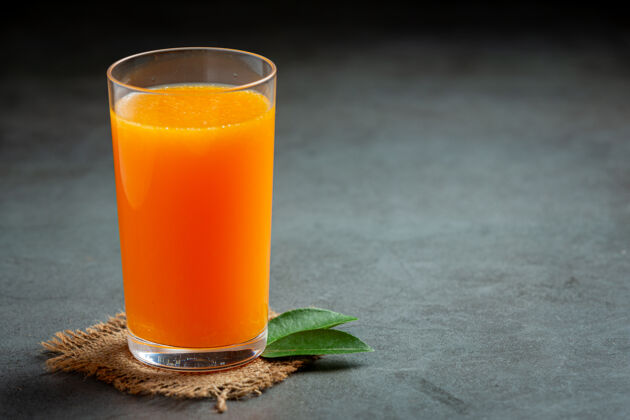 绿色新鲜的橙汁在黑暗的背景玻璃切割玻璃杯水平