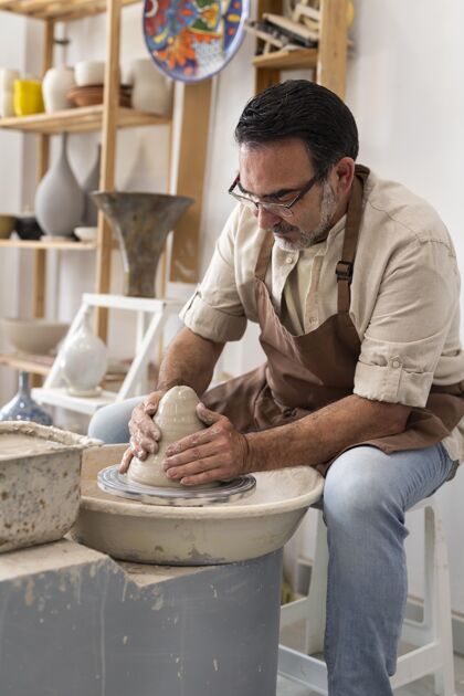 工艺中等身材的男人在室内做陶器工匠艺术品里面