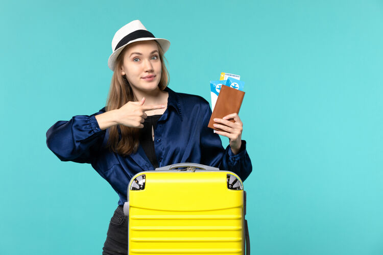 准备正面图年轻女子拿着机票 准备在蓝色地板上旅行 旅行 飞机 海上度假旅行旅行人举行