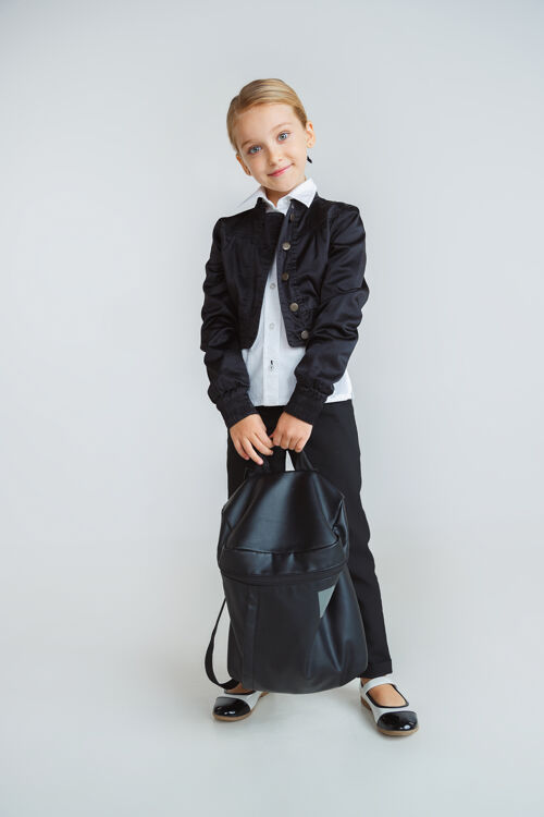 包穿着校服 背着背包在白墙上摆姿势的小女模特课学习人