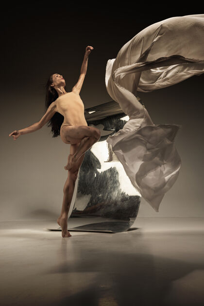 姿势年轻时尚的现代芭蕾舞演员在棕色的墙上用镜子伸展点年轻