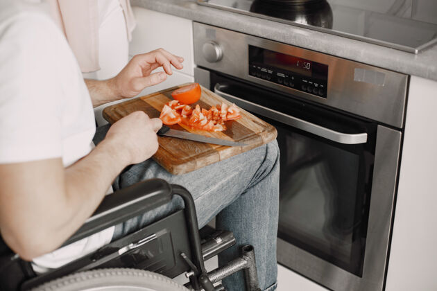 男人残疾人在厨房准备食物切蔬菜残疾轮椅男性