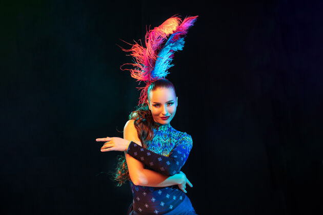 意大利嘉年华里美丽的年轻女子 霓虹灯下黑色墙壁上羽毛的时尚化装服装假日巴西乐趣