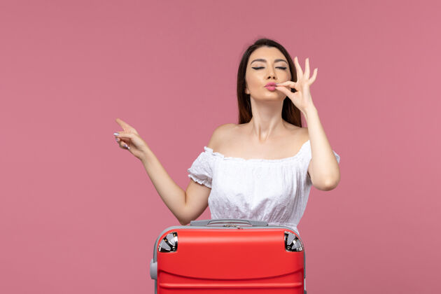准备正面图：年轻女性带着红色书包在粉色书桌上准备度假出国旅行海上旅行包成人旅行