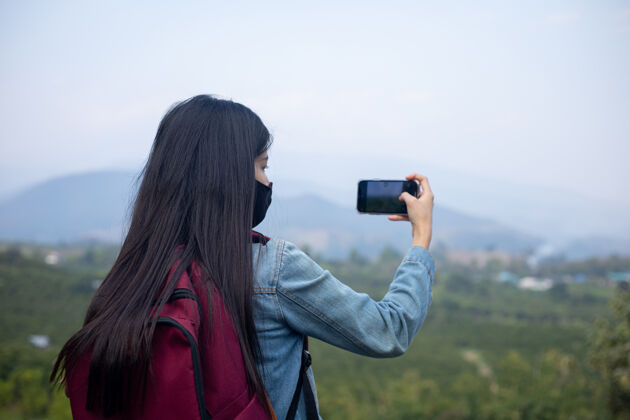 背包亚洲女游客戴着口罩看手机水平探索亚洲