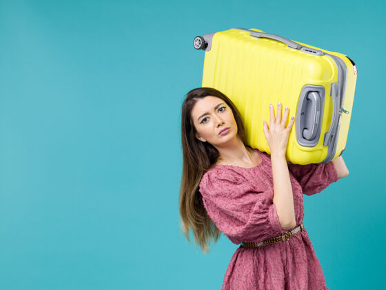 人正面图年轻女子带着她的黄色袋子在蓝色背景上度假夏季旅行人类之旅女人海肖像旅程美丽