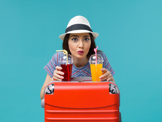 欢呼前景度假的女人拿着新鲜的果汁在蓝色背景的海上飞机上旅行夏天新鲜举行微笑