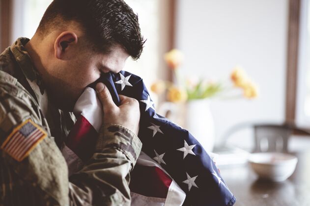 军官美国士兵手持美国国旗哀悼和祈祷花男性哀悼