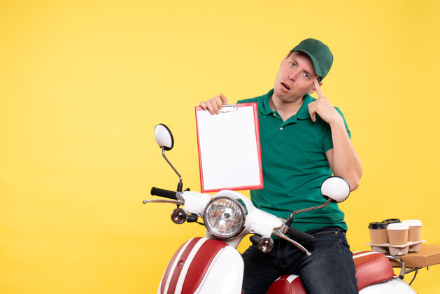 工作正面图：身穿绿色制服的年轻男信使拿着黄色的文件纸条通知摩托车工作