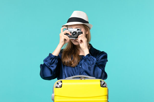 航行前视图年轻女子手持相机 在蓝色背景的女子海上旅行飞机上拍照肖像人旅程