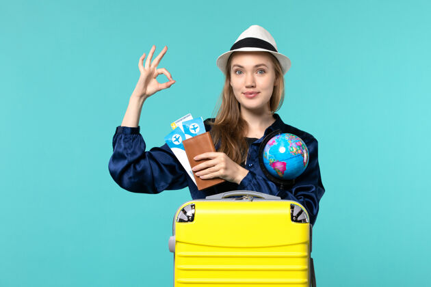 旅程前视图年轻女子手持机票和地球仪在淡蓝色背景飞机海上度假旅行成人举行女士