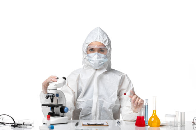 套装正面图：年轻女医生穿着白色防护服 戴着口罩 因为白色办公桌上的柯维德大流行柯维德-病毒健康医生大流行防护
