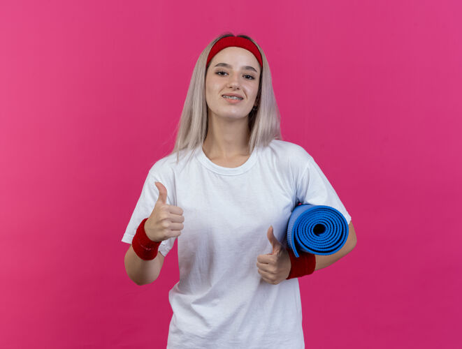 运动微笑的年轻白人运动女孩戴着背带和头带垫子腕带年轻