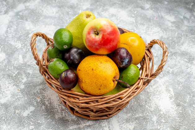 健康底部视图塑料柳条篮与苹果梨 李子和柿子在灰色的桌子上复制空间柑橘餐桌可食用水果