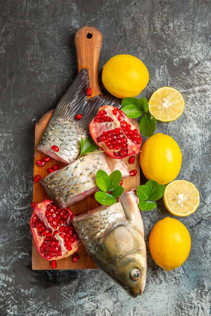 生的顶视图新鲜鱼片与石榴和柠檬在光表面顶级健康柠檬