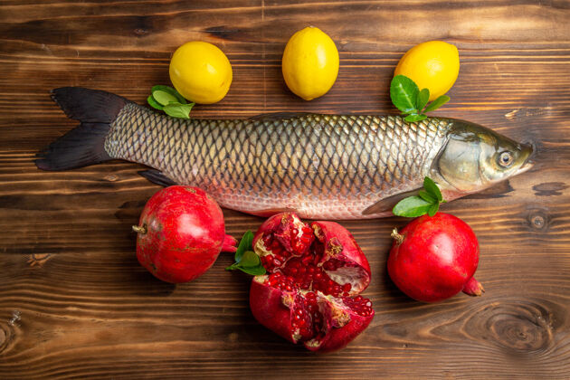 新鲜鱼木桌上的石榴柠檬鲜鱼俯瞰图海鲜海洋蔬菜