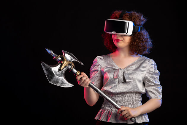 虚拟现实年轻女性戴着vr头戴式战斧在黑暗的表面黑人战斗