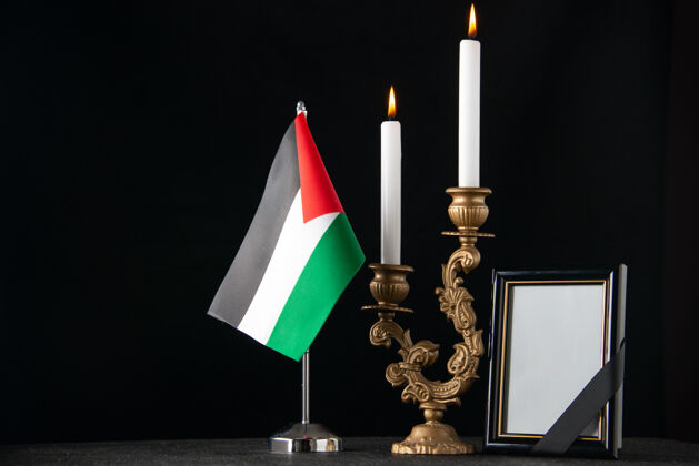 烛台前视图燃烧着巴勒斯坦国旗和相框黑暗的表面蜡烛框架正面风景