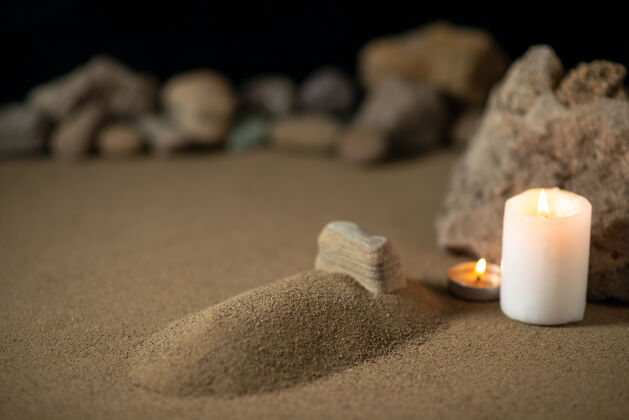 放松小小的坟墓 用蜡烛和石头在沙滩上埋葬战争的死神石头死亡鹅卵石