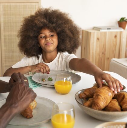 家庭卷发小女孩在吃早餐娱乐休闲年轻人