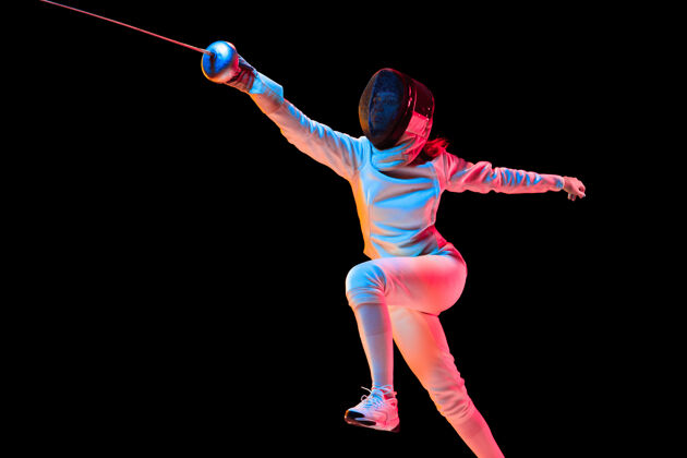 运动员攻击身穿击剑服装的少女 手拿剑 黑色背景 霓虹灯年轻模特在运动中练习和训练 动作广告空间运动 年轻 健康的生活方式头盔女孩技能