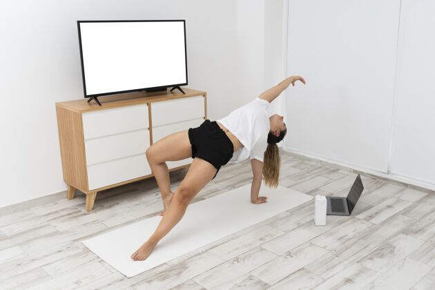 地板运动型女人在家做瑜伽智能电视精神室内