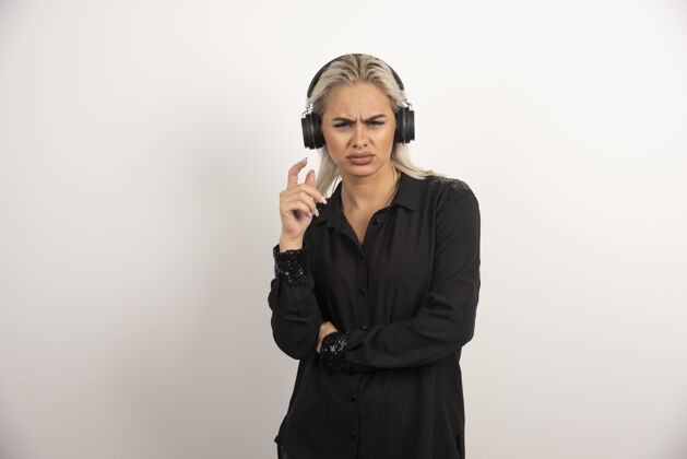 成人不高兴的妇女与耳机站在白色背景上高品质的照片不高兴人音乐
