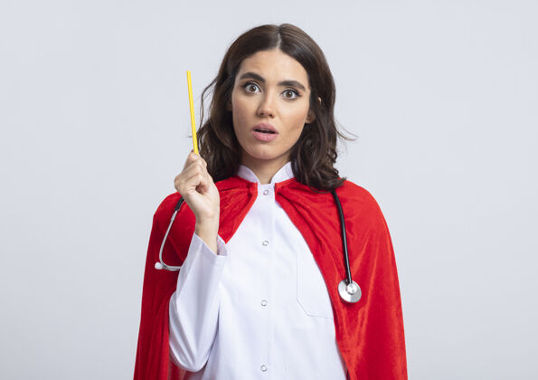 惊喜一个穿着医生制服 穿着红色斗篷 手持听诊器的白人超级英雄女孩拿着铅笔制服听诊器铅笔