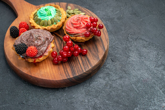 饼干前视图美味奶油蛋糕与浆果在黑暗的背景甜点可食用水果草莓