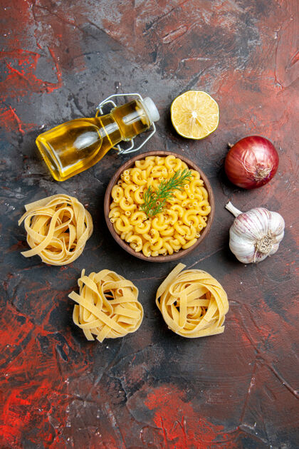 混合在混合色背景上的棕色碗和葱柠檬蒜油瓶中的三块生肉片和蝴蝶面的垂直视图食物碗餐