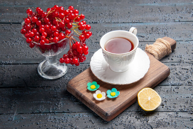 早餐底图一杯红醋栗一杯茶在砧板上一片柠檬在黑暗的背景下盘子盘子食物