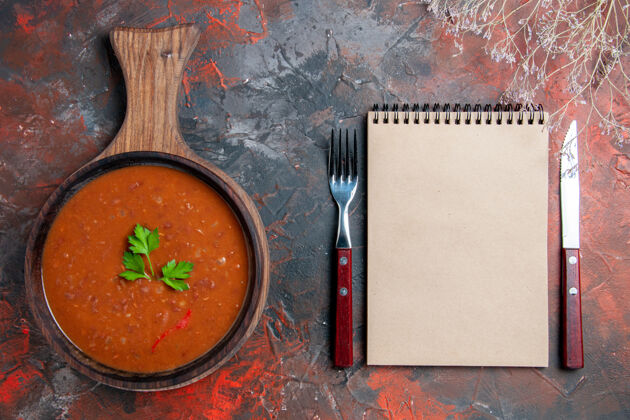 混合在棕色砧板和混合色背景上的笔记本上俯瞰经典番茄汤黑板背景西红柿汤