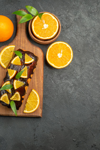 可食用水果整个美味蛋糕和切柠檬的垂直视图在黑色背景的砧板上新鲜切割柑橘