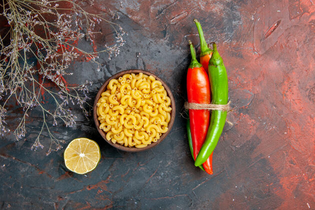 蔬菜不同颜色和大小的生面团辣椒的俯视图 在混合色背景上用绳子和柠檬绑在一起领带绳索不同