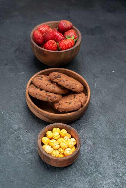 可食用坚果前视图新鲜草莓和饼干在黑暗的背景早餐黑暗饼干