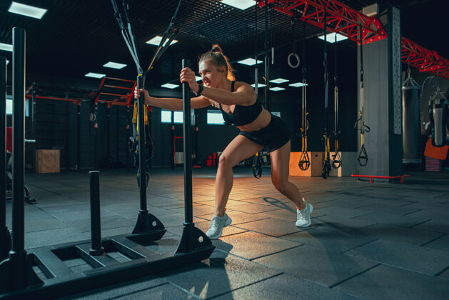 健身房年轻肌肉发达的女人在健身房练习运动员重活动