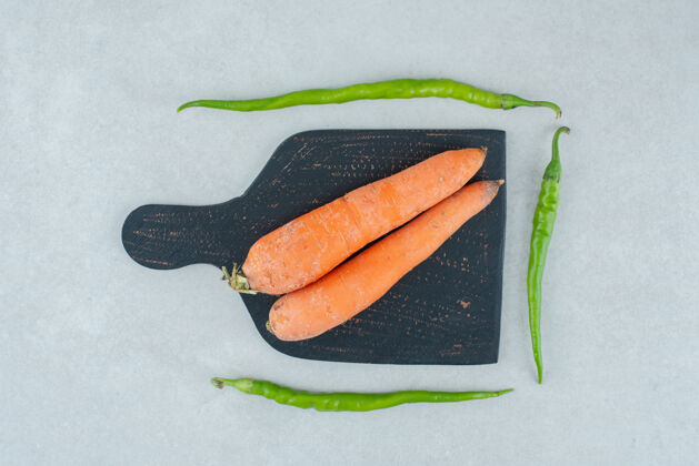 胡萝卜成熟的胡萝卜和胡椒放在深色的木板上天然有机蔬菜