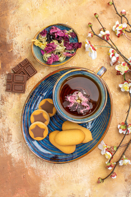 餐厅各种饼干的立面图一杯茶和鲜花巧克力条放在五颜六色的桌子上美味酒吧碗