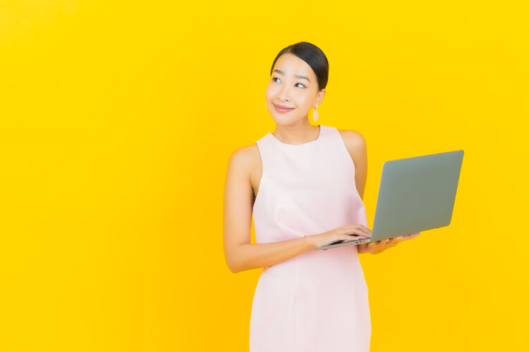 笔记本电脑肖像美丽的亚洲年轻女子微笑着用黄色笔记本电脑成年人快乐黄色