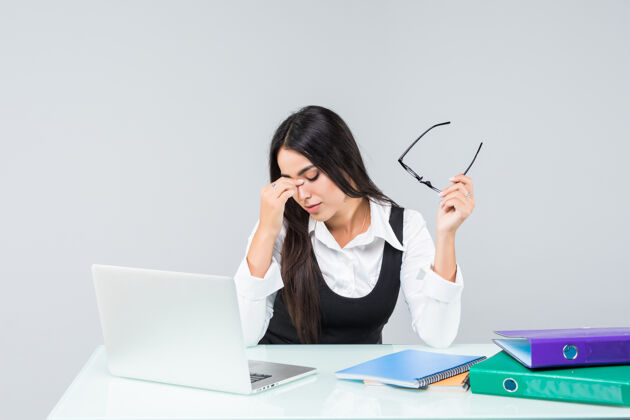 计算机年轻的女商人觉得累了 抱着头在工作台上孤立的白色悲伤脸员工