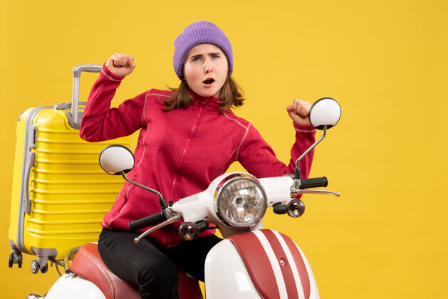 车辆前视图：骑着轻便摩托车的年轻女孩展示着胜利的姿态成人训练传送带