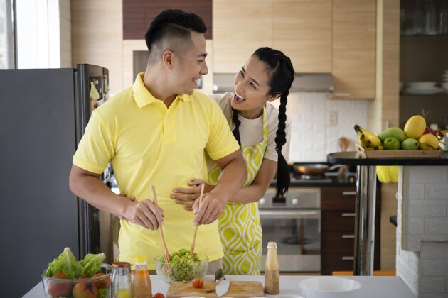 女人中景的快乐夫妻在厨房洛杉矶室内活动配料