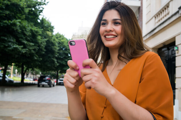 智能年轻女子在街上户外散步时使用手机的画像城市文字电话