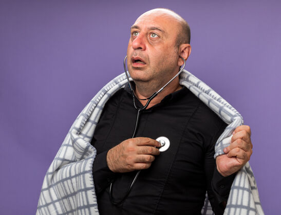 隔离震惊的成年病高加索男子包裹在格子布测量心跳听诊器看一边隔离在紫色墙上复制空间测量白种人疾病