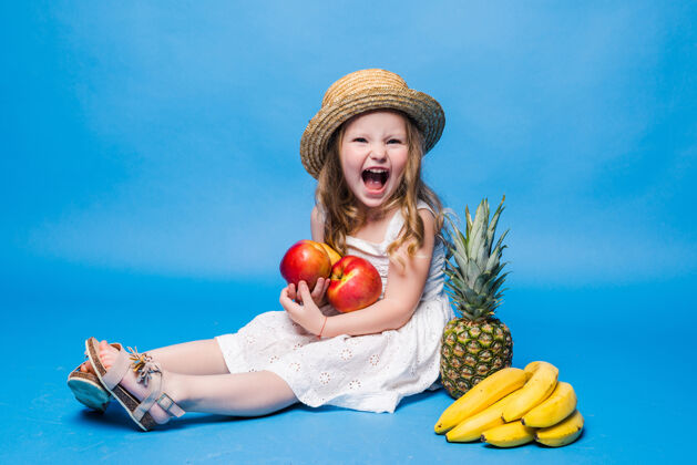 美丽可爱的小女孩和水果隔离在蓝色的墙上菠萝可爱孩子